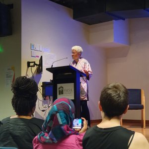 Professor Patricia Hill Collins speaks at a podium at the front of a room