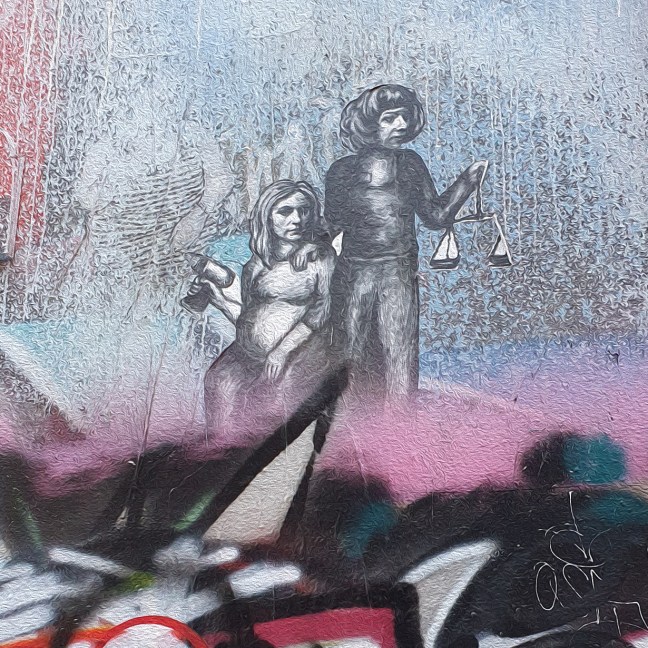 Paste-up drawing on a wall, showing two women. One woman is sitting and holds an electric drill. The other woman stands and holds scales of justice