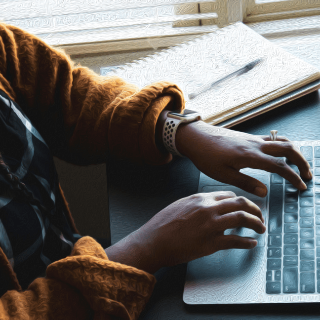 Hands of a person of colour typing on a laptop